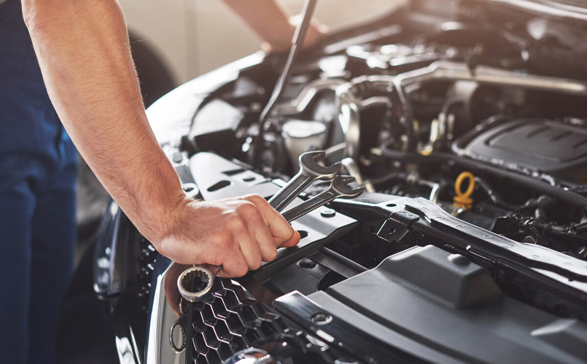 Automehāniķis ar instrumentiem pie auto motora