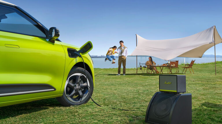 Ģimene atpūšas pie dabas blakus uzlādējošam elektroauto