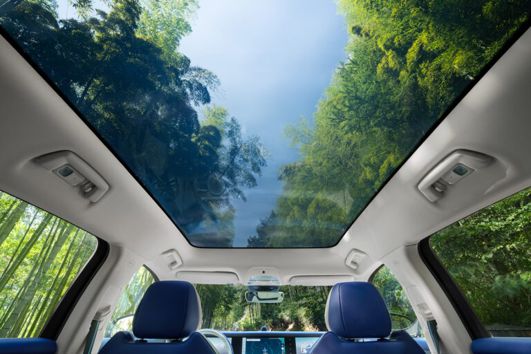 Panoramic roof of Voyah Free car with view of sky and trees, creating sense of spaciousness.